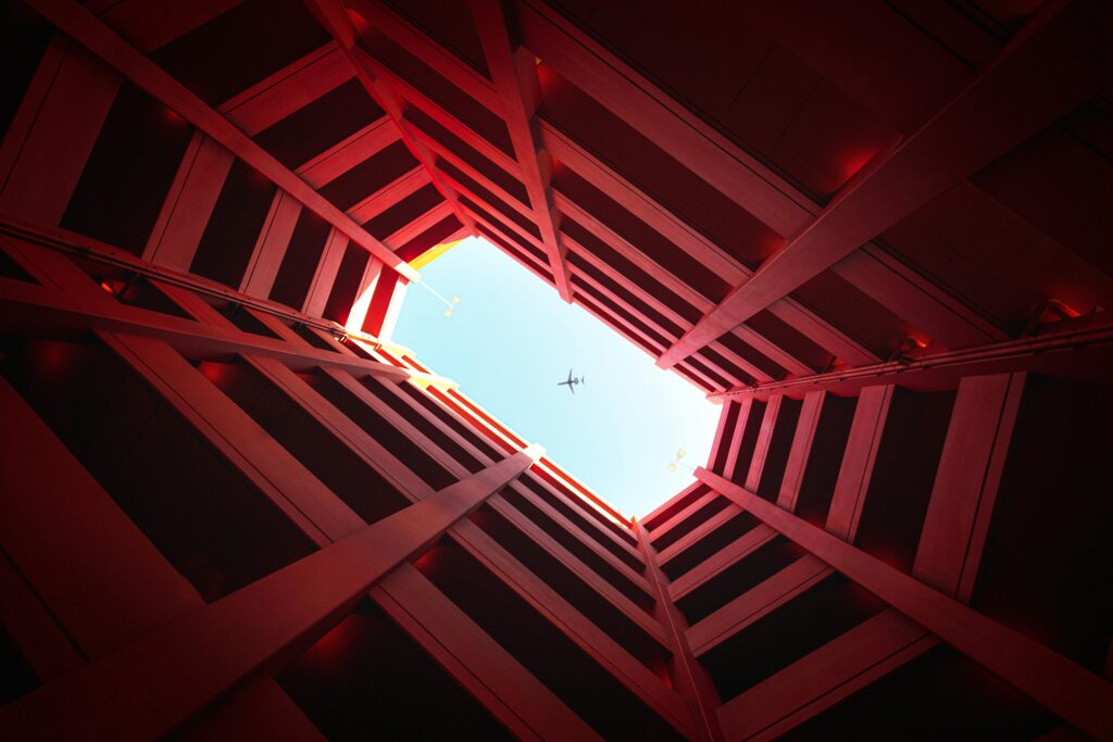 pexels-photo-2397650-2397650 Unique perspective of an airplane flying above geometric red architecture